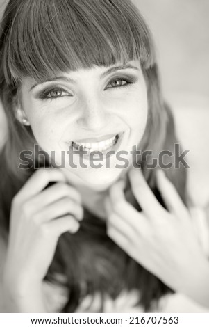 Black and white portrait of a beautiful, caucasian, young, long haired woman wearing a white dress, looking happy
