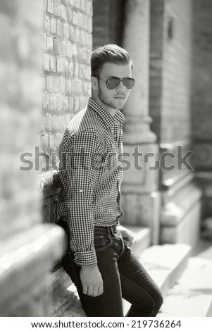 Black and white photo of a handsome young man wearing a shirt and jeans. Street shooting in Timisoara, Romania