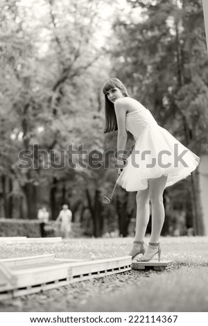 Black and white photo of a beautiful, caucasian, young, long haired woman posing in the park, wearing a white dress