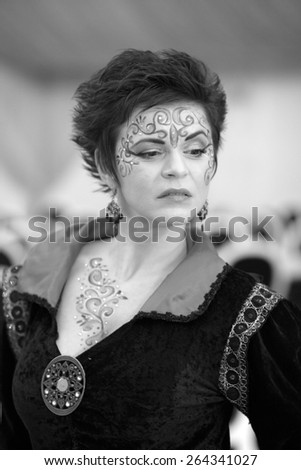 Photo session of an expressive, short haired, brunette woman painted on the face and body. Black and white photography