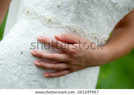 Close up photo of a hand of a woman wearing a wedding dress with natural background
