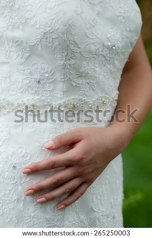 Close up photo of a hand of a woman wearing a wedding dress with natural background