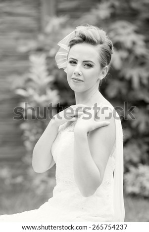 Photo of a beautiful, caucasian, long haired woman wearing a wedding dress, looking happy and melancholic. Black and white photography