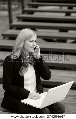 Blonde business woman with laptop and phone. Black and white photography