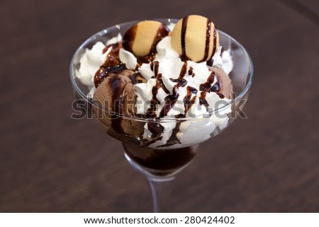 Ice cream with white cream and chocolate sauce in a glass cup