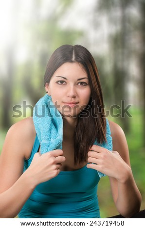 Happy young woman satisfied ofter working out outdoors. Holding the towel around her neck
