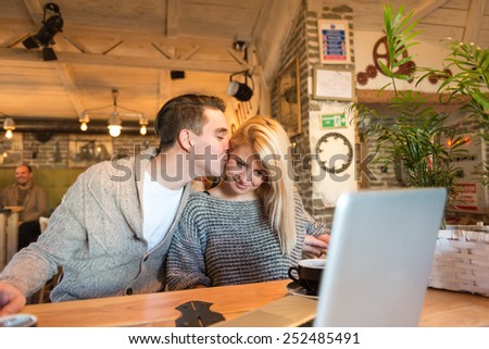 Happy couple in the cafe, cheek kissing. The foreground is blurred, narrow depth of field, only used natural  light.