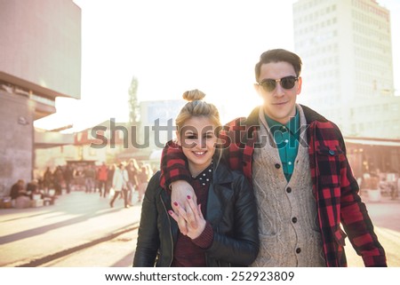 Happy stylish hipster couple walking on the streets. Warm tones, a little bit enhanced on the background. Lens flare added to enhace the sunlight effect