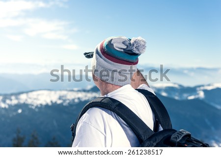 Middle aged man looking far away from the top of the mountain. Warmer highlights, shallow depth of field.