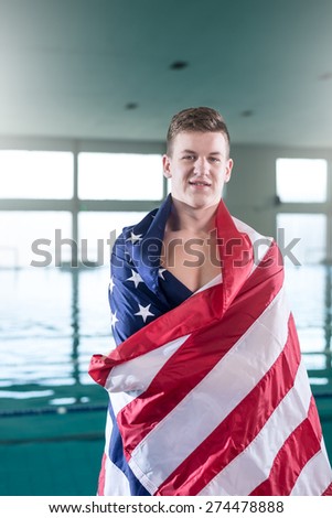 Proud teen boy standing by the pool, covered with USA flag.
