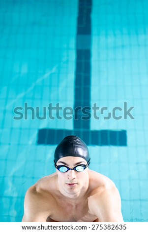 Professional swimmer preparing for a swimming race and diving off the starting block. A lot of copy space, selective focus