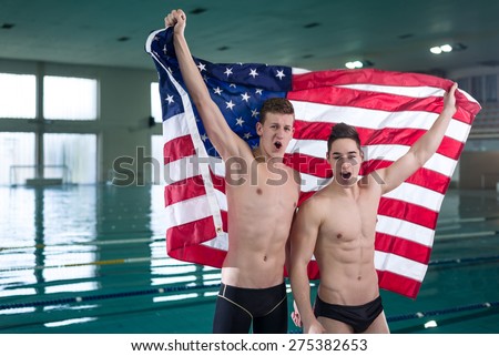 Two young swimmers by the pool raised USA flag in the air. Winners concept.