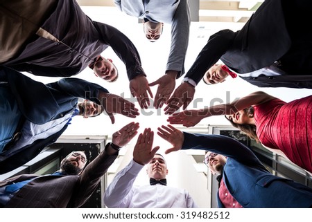 Together we are stronger. Groupe of young people gesturing the power of togetherness. Low, wide angle shot, selective focus on their hands, narrow depth of filed.