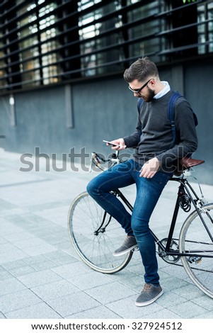 Shot of a businessman using his cellphone while going to work with his bicycle.