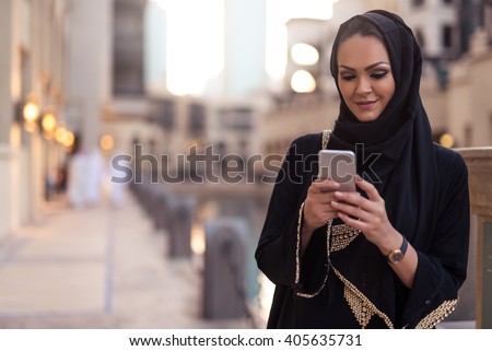 Muslim woman messaging on a mobile phone in the city.
