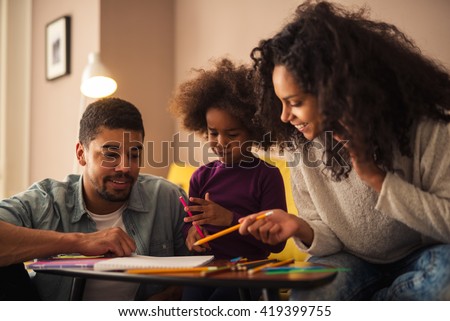 Mom and dad drawing with their daughter.
