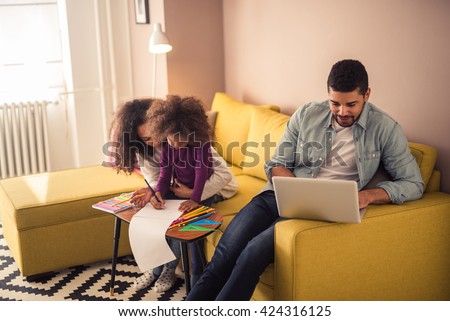 Mom drawing with her kid while dad is working on a laptop.