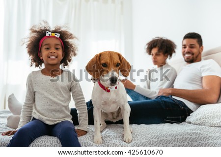 Family having fun with his pet in a bed.