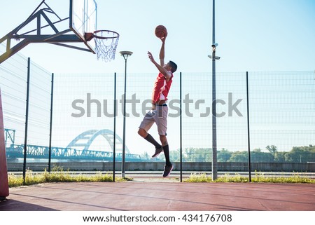 Young african american basketball player scoring a slam dunk.