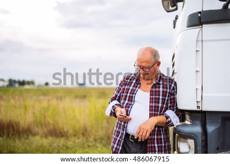 Senior truck driver checking his mobile phone.