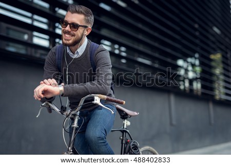 Handsome hipster enjoying city ride by bicycle.