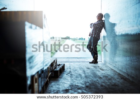 Senior truck driver standing with crossed arms.