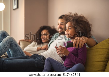 Happy african american family relaxing and watching tv.