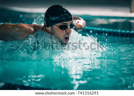 A young athletic man swimming in an indoor pool.