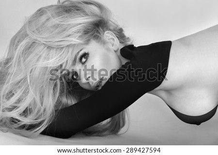 Portrait of a beautiful long-haired blond woman in a black T-shirt sensually viewing the lens side