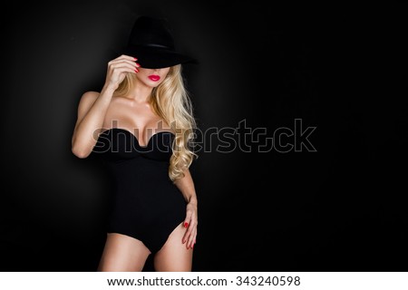 Beautiful blond woman girl sexy model dressed in black lingerie outfit body swimsuit and black hat and long boots knee