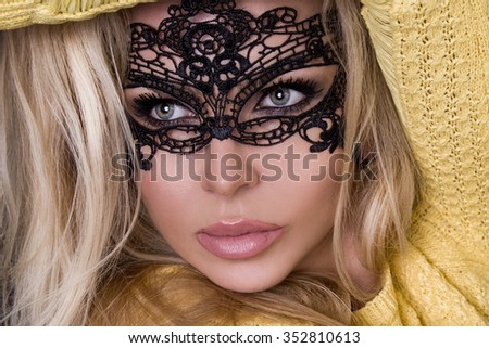 Portrait of the beautiful blond hair sexy women, young girl model in a black mask carnival ball in tight elegant dress in yellow on a black background