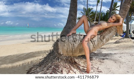 Beautiful young very sexy blond hair female model amazing girl lies on an old tree on the palm tree with an amazing view of the  sea  in the fleshy nude erotic crystal lingerie with long shapely legs