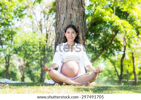 Pregnant beautiful woman yoga outdoors on the grass in sunny summer day, healthy pregnant woman doing yoga in nature outdoors.
