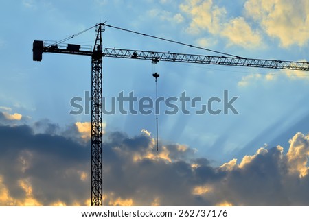 Silhouette of construction crane and the rays of the sun