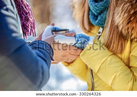 couple in the winter park. Winter forest, park. Man and woman hugging in the park in winter.The girl and the guy pours tea from a thermos. Keep a cup of tea in his hands. Individuals can not see.
