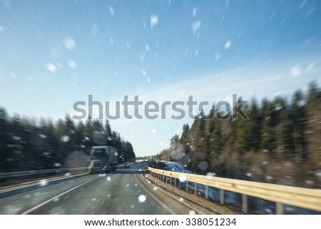 Winter road. Motion blur. On the road going truck cars. Snow, winter road. Around the fir forest. Highway, Route. Copy space. Background winter or on automotive topics.