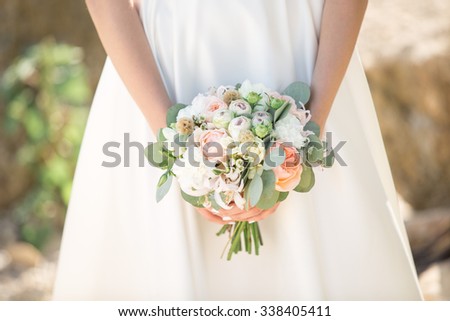 Bride boho style. Those girls are not seen are only visible hand with a bouquet and a long white dress. Bouquet of peach roses. The girl flowing white dress, photographed in nature.