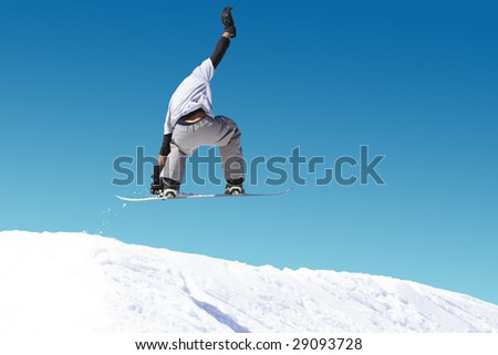 Young male snowboarder performing jump, blue sky background.