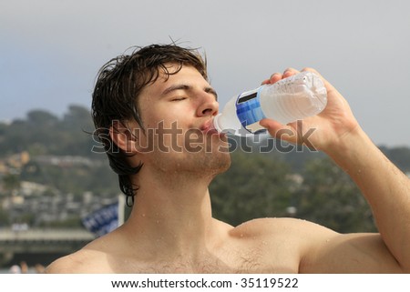 Thirsty man drinking water from water bottle on the beach