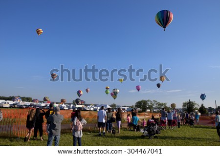Whitehouse Station, New Jersey, USA - July 24, 2015: People watching the mass ascension launch of hot air balloons at the New Jersey Ballooning Festival in Whitehouse Station, NJ on July 24, 2015.