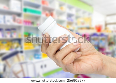hand holding medicine bottle in pharmacy
