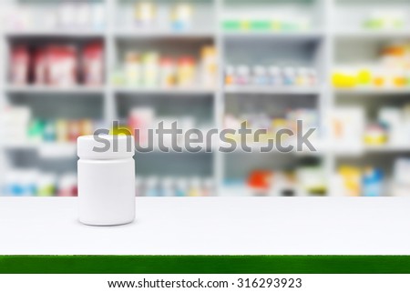 Blank white medicine bottle on counter with blur shelves of drug in the pharmacy drugstore background