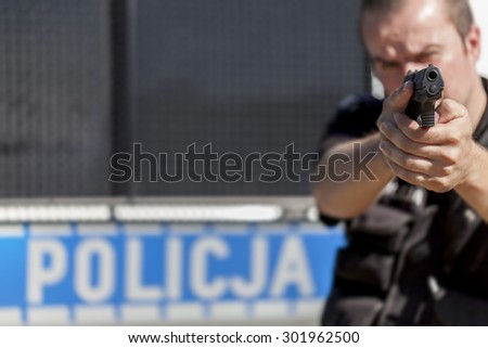 A police officer aiming with gun (focus on gun)