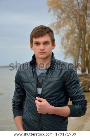 A young man in front of the sea. A young man in a leather jacket in front of the sea and sky