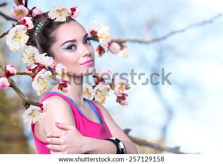 Girl in a pink shirt with spring flowers. Fowering branch of apricot