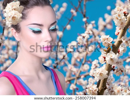 Girl in a pink shirt with spring flowers. Butterfly on a flowering branch of apricot