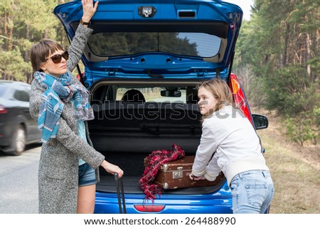 Mother and daughter traveling by car with suitcases in the spring.