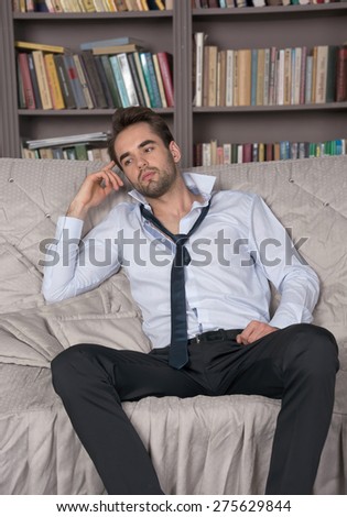 Young man in a suit lying on the sofa in a library