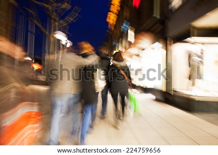 Shopping crowd walking on sidewalk at dusk