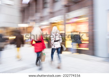 A young shoppers walking against shop window